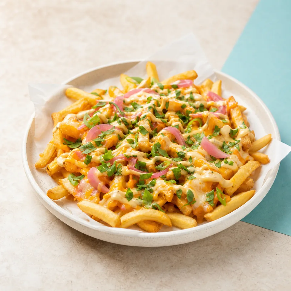 Loaded fries topped with sauce, herbs and pickled onions